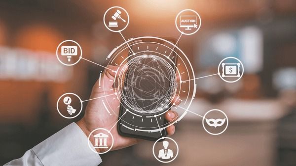 En hand håller i en smartphone med grafik för onlineauktioner och budgivning.